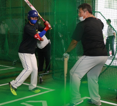 ソフトボール部の学生（左）にバッティングを教える山崎さん＝岐阜市中鶉１の岐阜聖徳学園大で