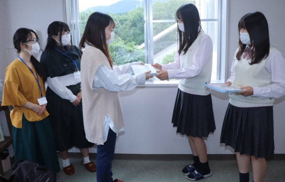 皇学館大生からチラシを受け取る高校生＝伊勢市黒瀬町の伊勢学園高で