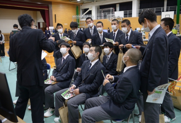 企業の担当者（左）から、仕事内容の説明を受ける生徒たち＝高山市の高山西高で
