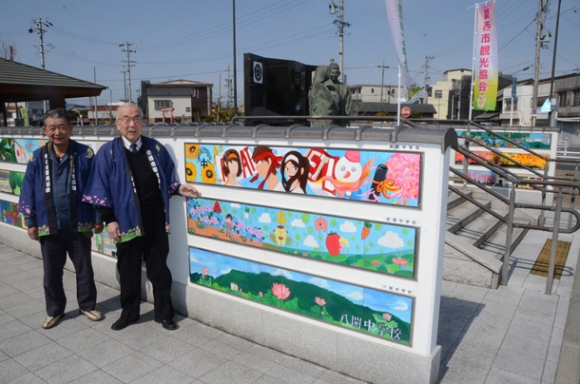 信長像を囲むタイル絵を紹介する加藤さん（右）ら関係者＝愛西市勝幡町の名鉄勝幡駅前広場で