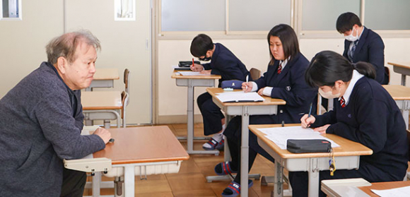 添乗員の仕事について説明する小田さん（左）＝伊勢市の皇学館中で