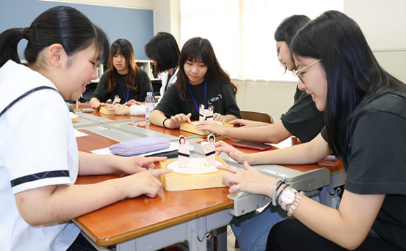 紙相撲で遊ぶ生徒たち＝伊勢市の皇学館中で