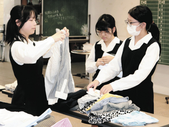 長机に並んだ服を手に取る生徒たち＝昭和区の南山高・中女子部で
