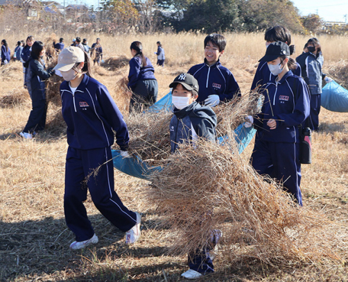 集めた草を運ぶ生徒たち＝四日市市西坂部町で