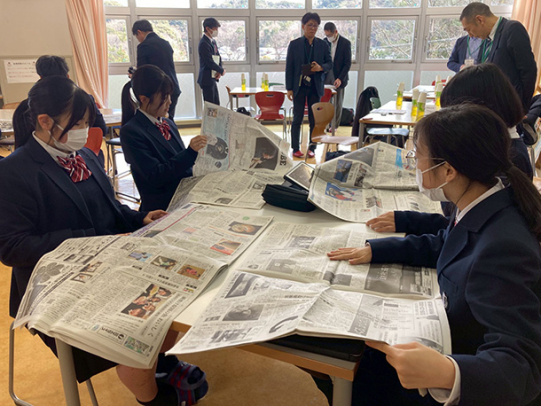 新聞を広げ、自分の将来につながりそうな記事を探す生徒たち＝伊勢市の皇学館中学校で