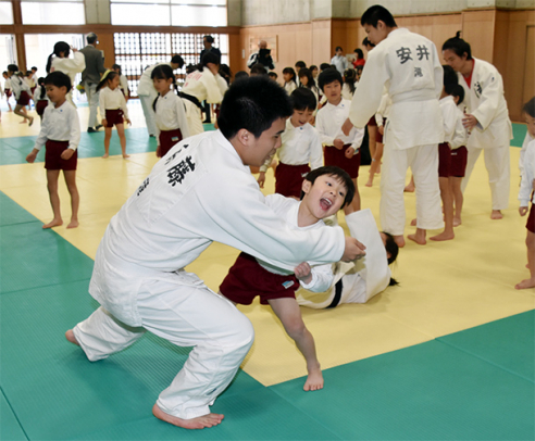 柔道部員を相手に投げの練習をする園児たち=江南市の滝学園柔道場で