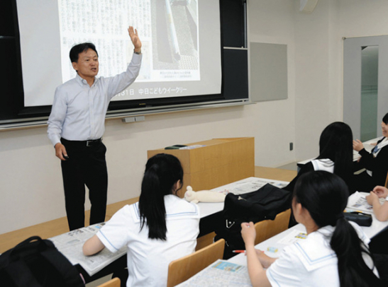 生徒に新聞の作り方を伝える鬼頭さん（左）＝瑞穂区の名古屋葵大で