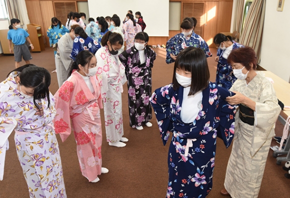 講師の指導で、腰ひもの結び方を体験する生徒ら=津市半田のセントヨゼフ女子学園中で