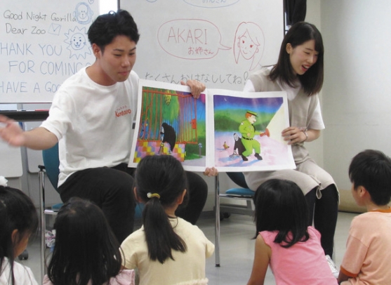 子どもたちに英語の絵本を読み聞かせる学生＝東区大幸南で