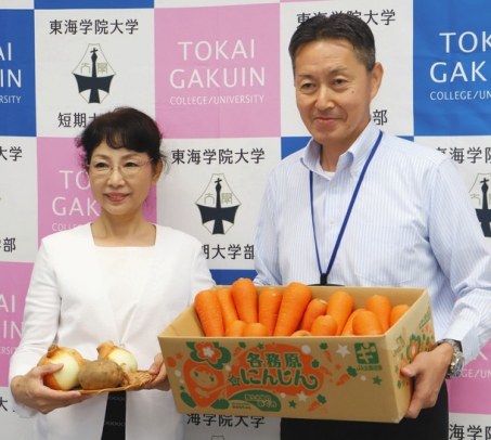 各務原市産の野菜を手にする神谷学長（左）と村瀬支店長＝各務原市の東海学院大で