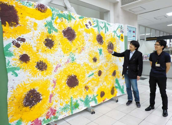 子どもたちが手形を押して書いたヒマワリの絵＝豊明市役所で