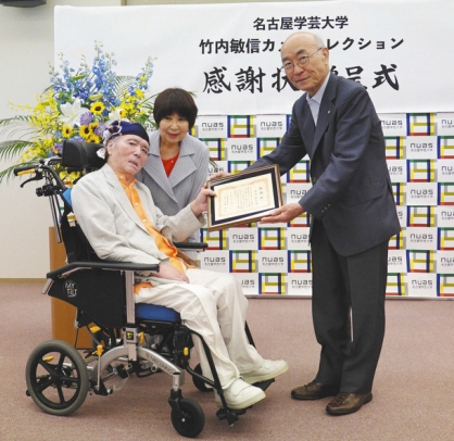 杉浦学長(右)から感謝状を受ける竹内さん(左)と妻昭子さん=日進市の名古屋外国語大で