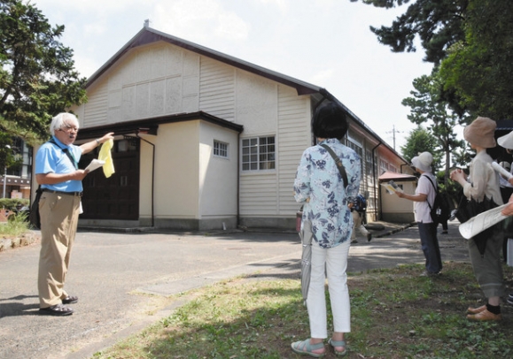 渡辺会長(左)の案内で、かつて教導学校大講堂として使われた建物を見学する参加者＝豊橋市の愛知大豊橋キャンパスで