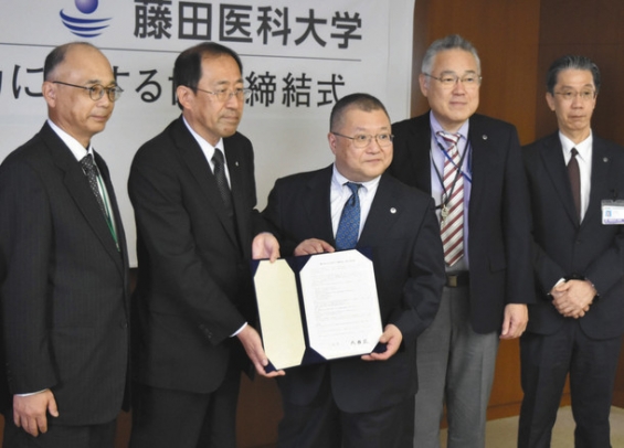 協定書を手にする成瀬町長（左から２人目）と才藤学長（同３人目）＝豊明市の藤田医科大で