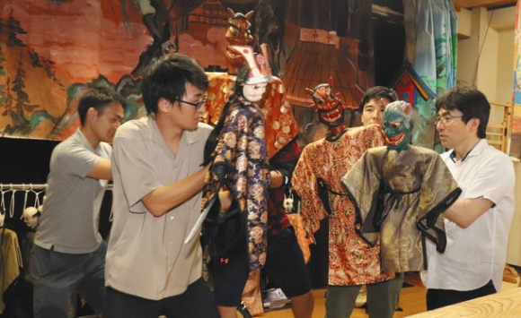 保存会員(右)から人形の動かし方を教わる学生=白山市東二口歴史民俗資料館で