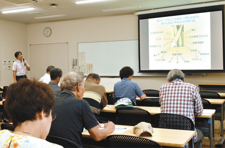 作物の成り立ちについて聞く参加者たち＝春日井市鷹来町の名城大農学部付属農場で