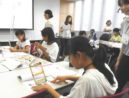 家の形をした紙製の振動実験教材を揺らして揺れを確かめる参加者＝名古屋市千種区の愛知工業大本山キャンパスで