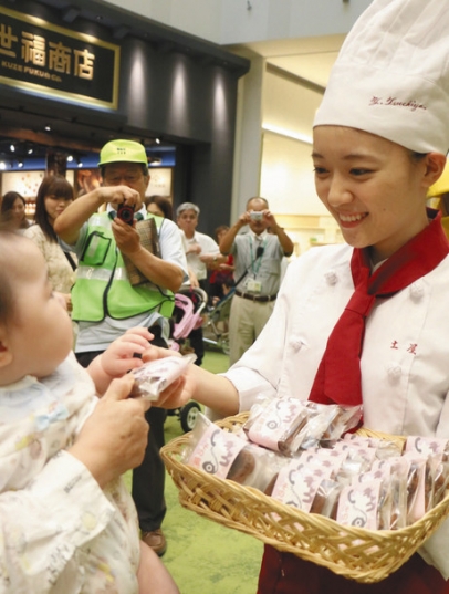 「ニセ電話詐欺に遭わないで」と手作りケーキを配る学生＝西区のｍｏｚｏワンダーシティで