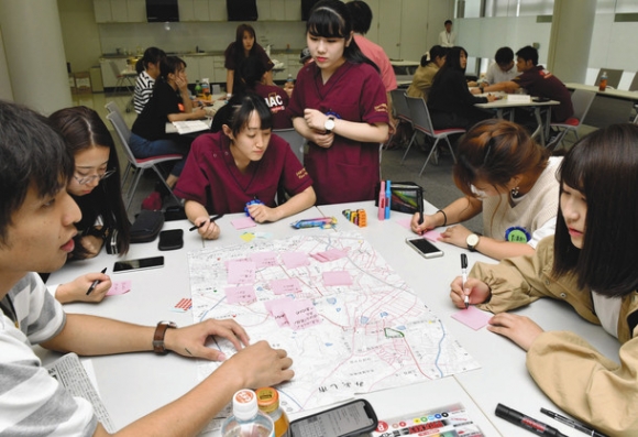 歩いて気付いた避難経路上の危険箇所について話し合う学生＝豊田市白山町で  