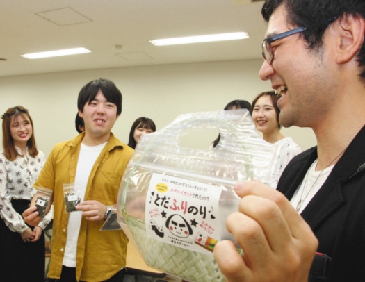学生のアイデアを取り入れた商品「とだふりのり」の試作品を披露する戸田理平商店の戸田国良さん（右）＝名古屋市昭和区の中京大で