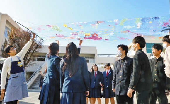 透明なシートに描いた絵を空に透かして眺める生徒ら＝武豊高で