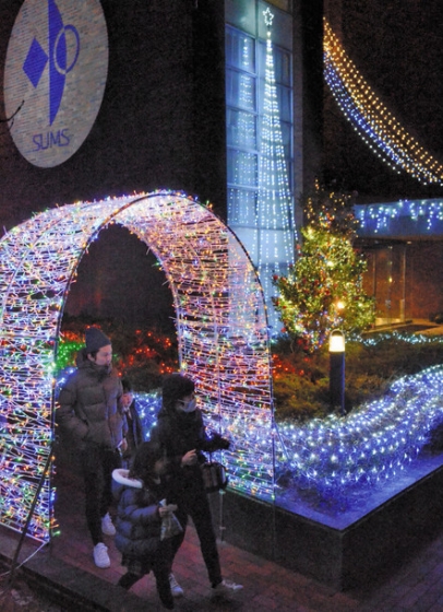 クリスマスにちなんだ電飾を楽しむ来場者＝鈴鹿市南玉垣町の鈴鹿医療科学大白子キャンパスで