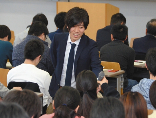 学生にマイクを向ける講師の黒崎さん＝鈴鹿市の鈴鹿医療科学大で