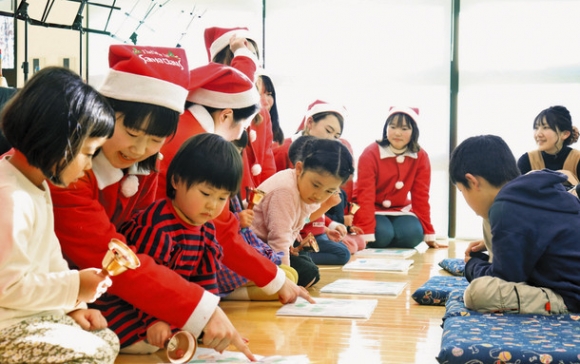ハンドベルを子どもたちに教える学生ら＝瑞穂市宮田の市図書館分館で