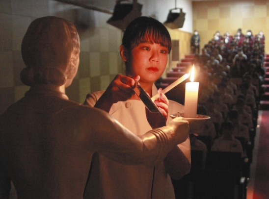 ナイチンゲール像からろうそくの火を受け継ぐ学生＝一宮市常願通５の一宮研伸大で