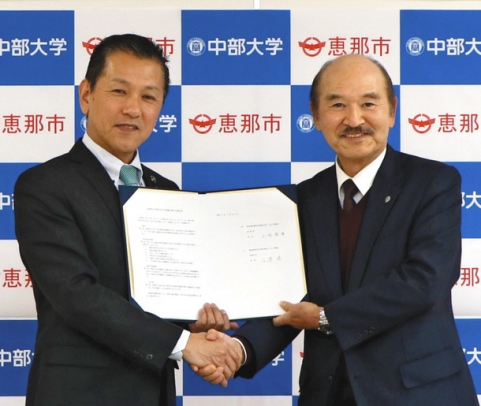 協定書に調印して握手を交わす小坂市長(左)と石原学長=恵那市役所で