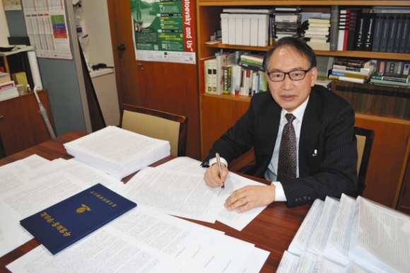 １０３９人分の卒業生へのメッセージに直筆でサインする亀山学長＝日進市の名古屋外国語大で