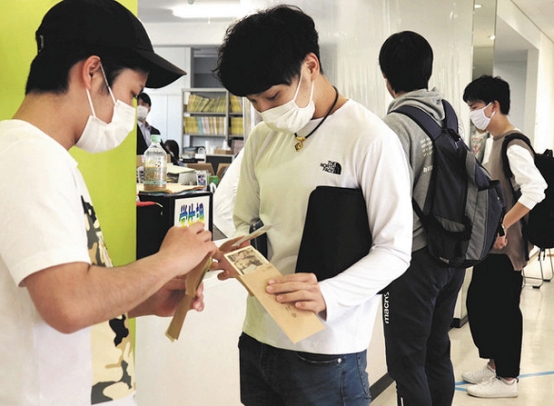 窓口で修学支援の３万円を受け取った学生＝11日午前、愛知県尾張旭市の名古屋産業大で