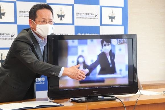 画面越しに神谷学長と締結の握手を交わす伊藤市長（左）＝美濃加茂市役所で
