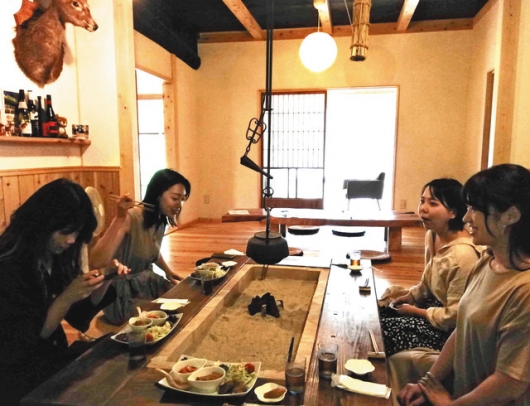 2019年7月、新しいレシピ作りに向け、山里カフェMuiでジビエ料理を食べる名古屋学芸大の学生たち=豊田市北小田町で(南さん提供)