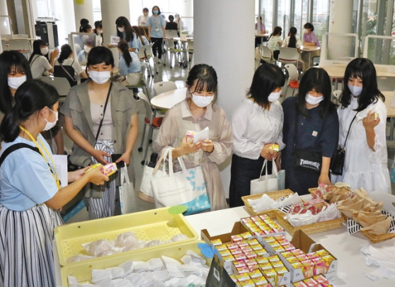 オープンキャンパスで、岡崎市の人気スイーツを受け取る見学者たち＝岡崎市の岡崎女子大・短大で