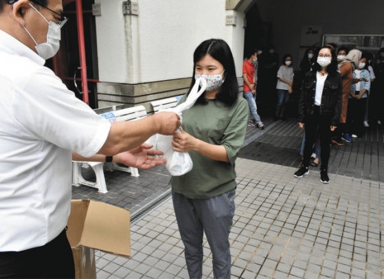 列をなして袋詰めにされた即席麺などを受け取る学生たち＝関市桐ケ丘で