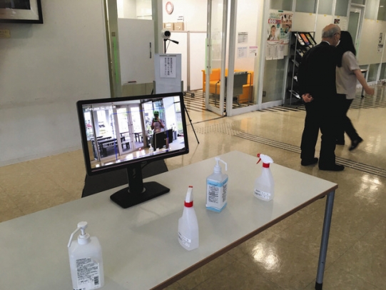 ヒューマンケア学部の入る建物入り口に設置された非接触式検温カメラとモニター=日進市の名古屋学芸大で