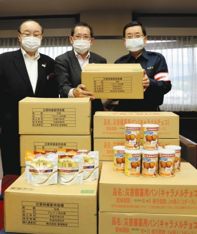 国島市長（右）に非常食を手渡す小井事務局長代理（中）＝高山市役所で