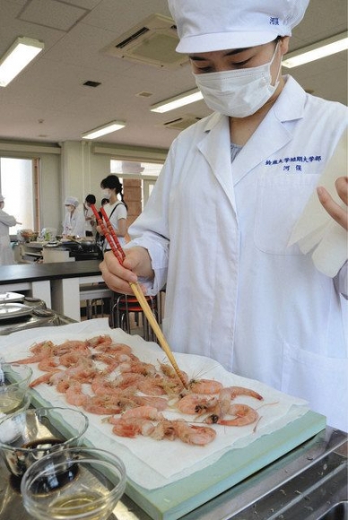 調理に使う尾鷲産のガスエビの下処理をする学生＝鈴鹿市の鈴鹿大で