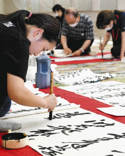 張り詰めた空気の中、真剣に筆を走らせる部員たち＝高山市中山町の光ミュージアムで