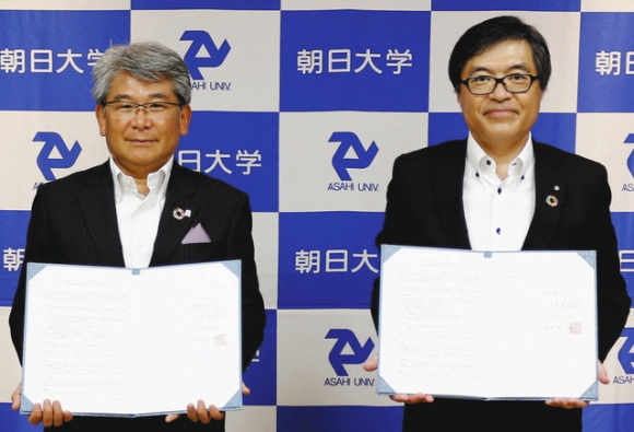 協定書に署名した田中社長(左)と大友学長=瑞穂市の朝日大で