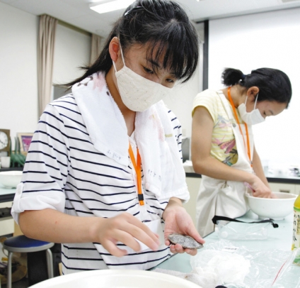紙やすりを使い、化石を磨く参加者＝岐阜市柳津町高桑西の岐阜聖徳学園大の羽島キャンパスで