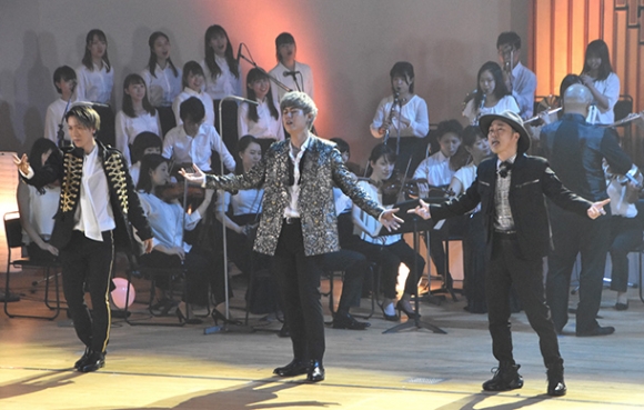 SEAMOさん(手前右端)やクールエックスのメンバーの後ろで演奏やコーラスをする学生たち=北名古屋市徳重の名古屋芸術大で