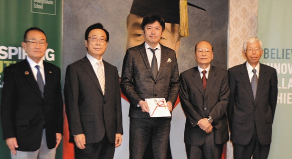 栗本学長（中央）に特別寄付金の目録を手渡した市岡会長（右から２人目）ら同窓会メンバー＝日進市の名古屋商科大で