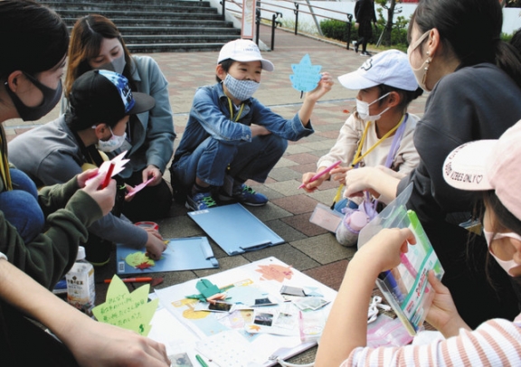 メッセージを書いたカードを見せ合う参加者=長久手市勝入塚で