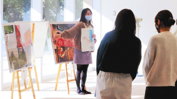 ギャラリーに展示した写真の前で、視察中に感じたことを話す磯野ゼミの学生＝守山区大森の金城学院大で
