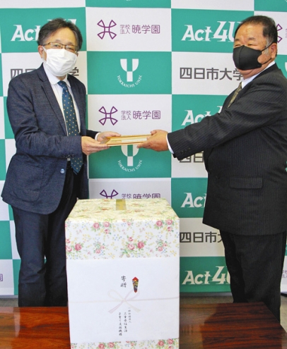 寄贈品目録を岩崎学長（左）に手渡す瀬崎相談役＝四日市市萱生町の四日市大で