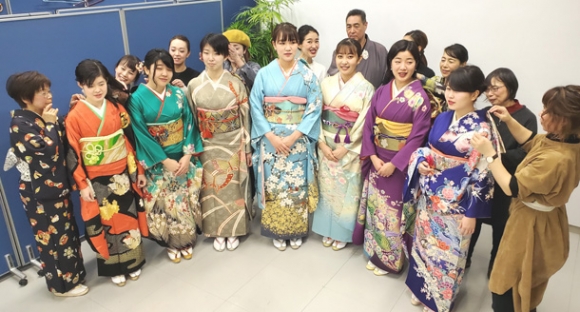 あでやかな振り袖に身を包んだ女子学生とボランティアの着付け師ら＝野々市市の金沢工業大で