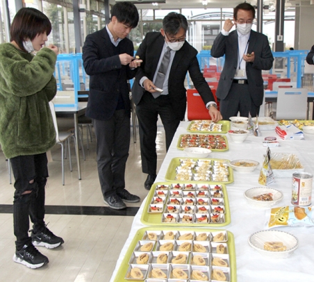 防災備蓄品をアレンジしたメニューを試食する大学関係者ら＝四日市市萱生町で