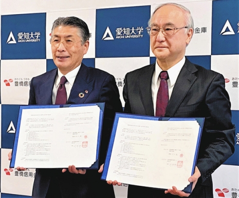 協定書にサインして記念撮影する豊橋信金の山口理事長（左）と愛知大の川井学長＝豊橋市の愛知大豊橋校舎で